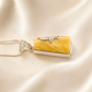 butterscotch amber necklace with silver setting on a beige fabric background