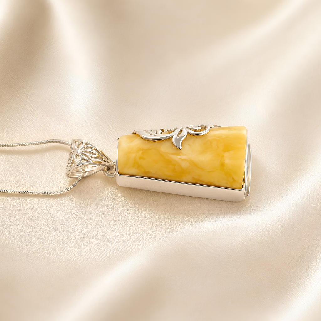 butterscotch amber necklace with silver setting on a beige fabric background