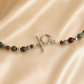 Beaded raven skull necklace with silver clasp on a beige fabric background