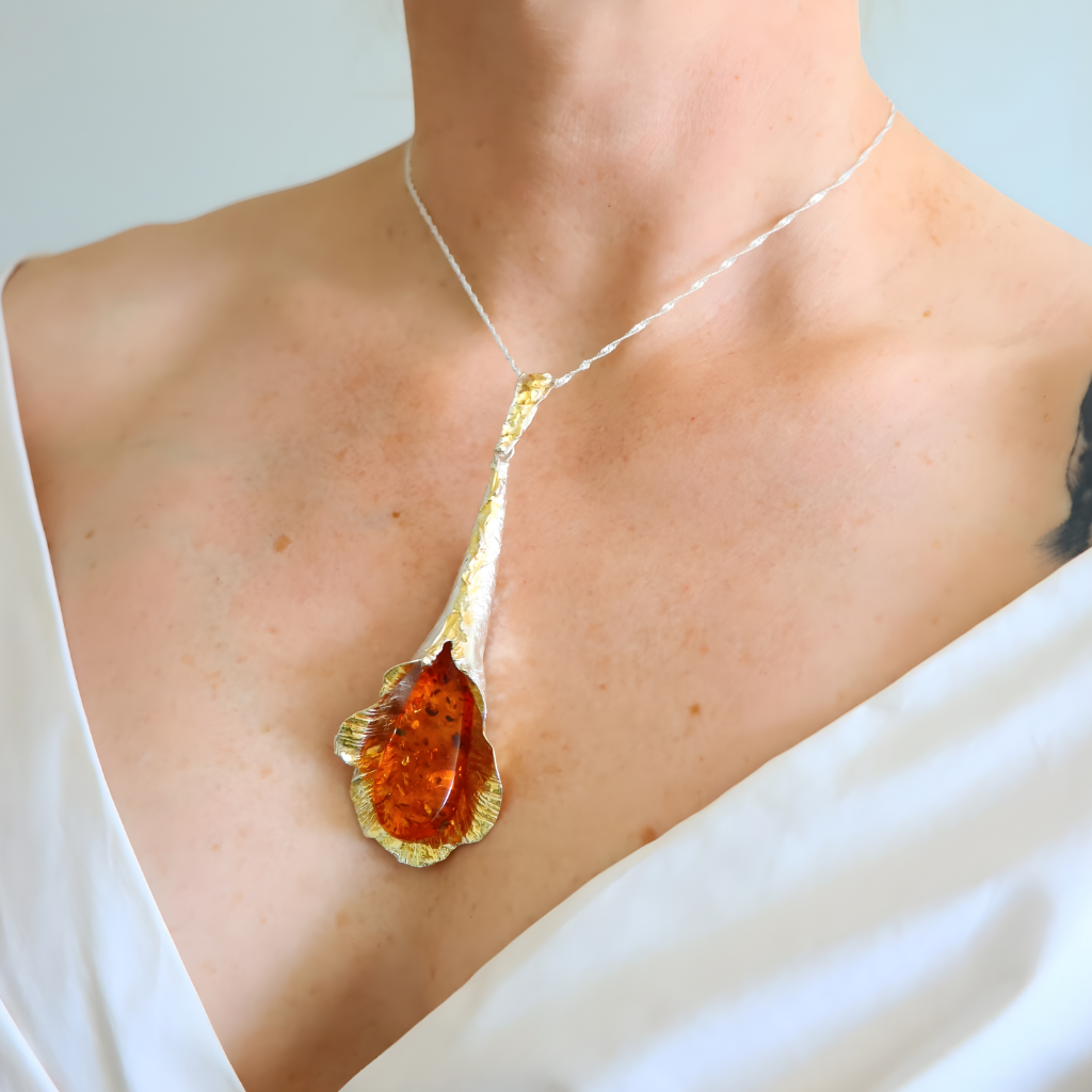 amber Necklace with a large pendant worn by a person in a white top.