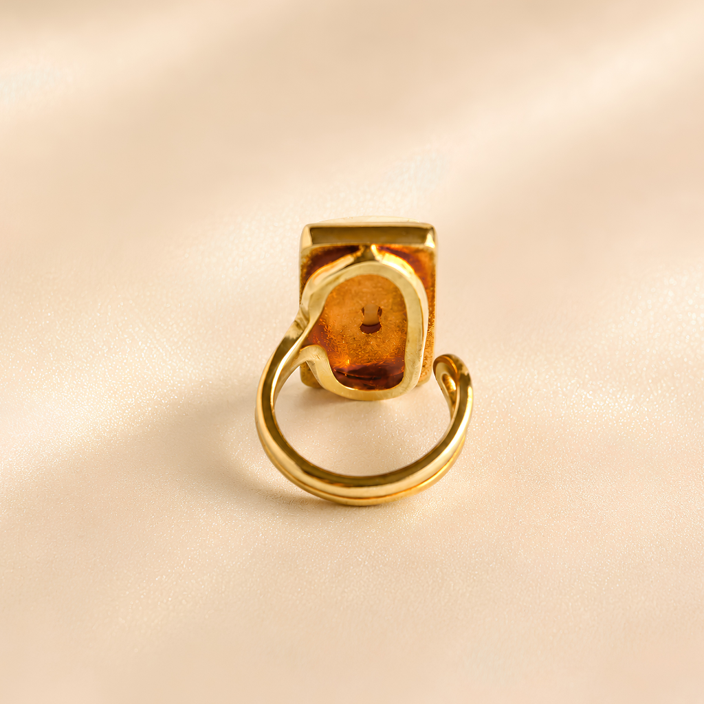 Back view of white amber ring showing amber underside and open adjustable gold-tone band.