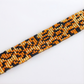 Close-up of a beaded bracelet with orange, black, and gold beads on a white background