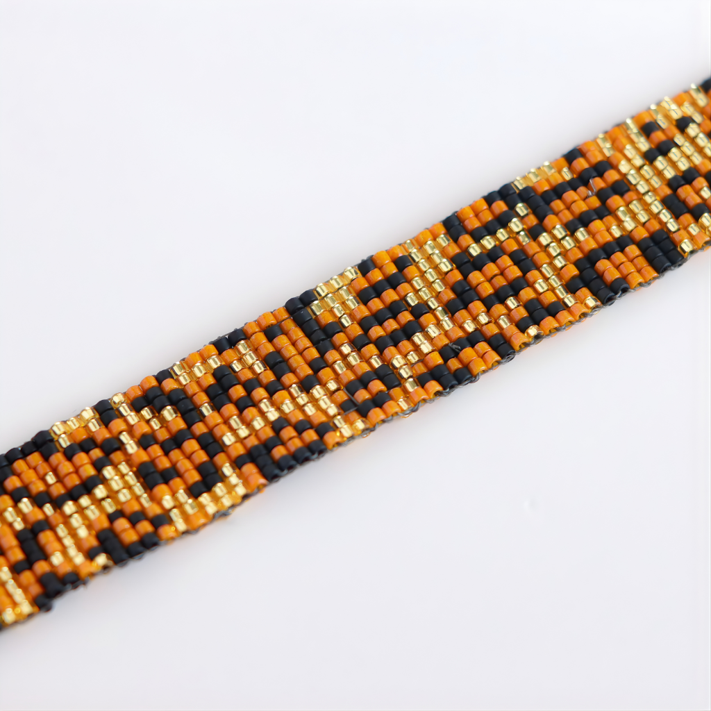 Close-up of a beaded bracelet with orange, black, and gold beads on a white background