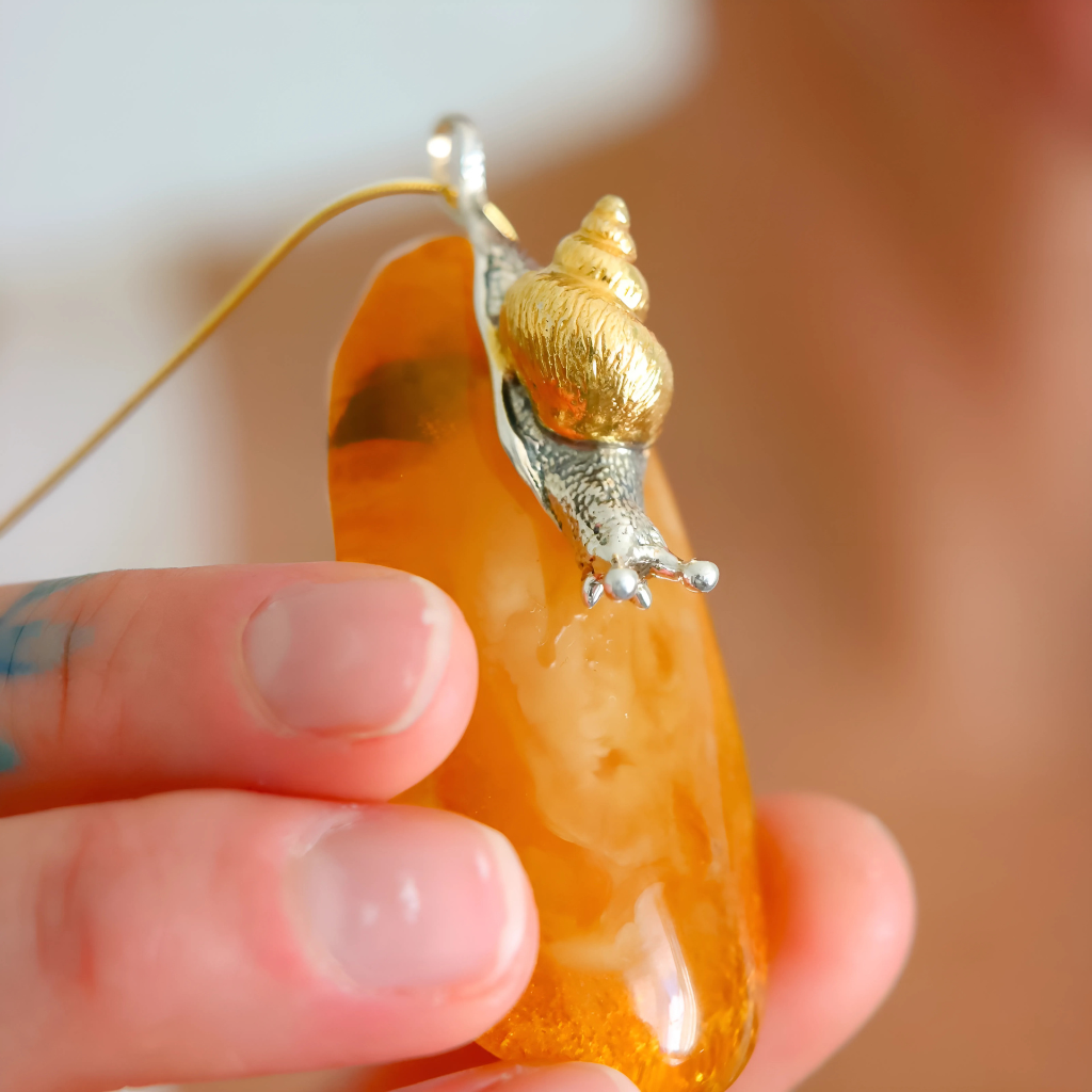 Gold and silver snail-shaped pendant statement necklace on a blurred background