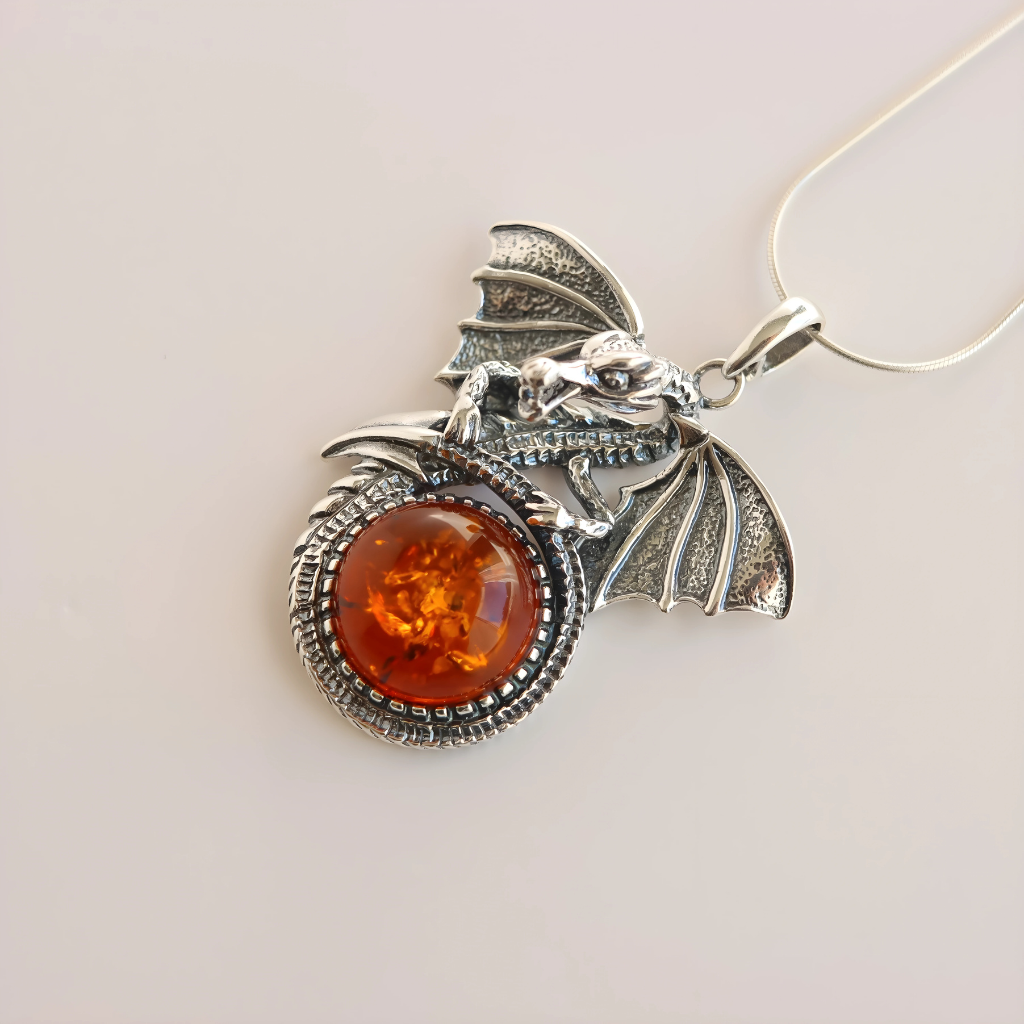 Silver dragon pendant with a round amber stone on a light gray background