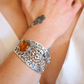 Silver spider amber bracelet with amber stone on a wrist against a white background