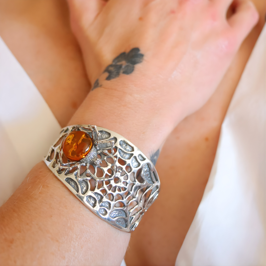 Silver spider amber bracelet with amber stone on a wrist against a white background