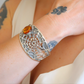 silver spider amber bracelet with a central amber stone on a wrist with tattoos
