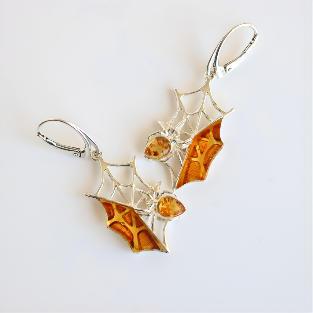 Silver and amber spider web amber earrings on a white background