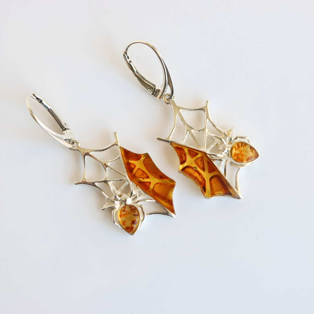 Spider web amber earrings with amber stones on a light gray background