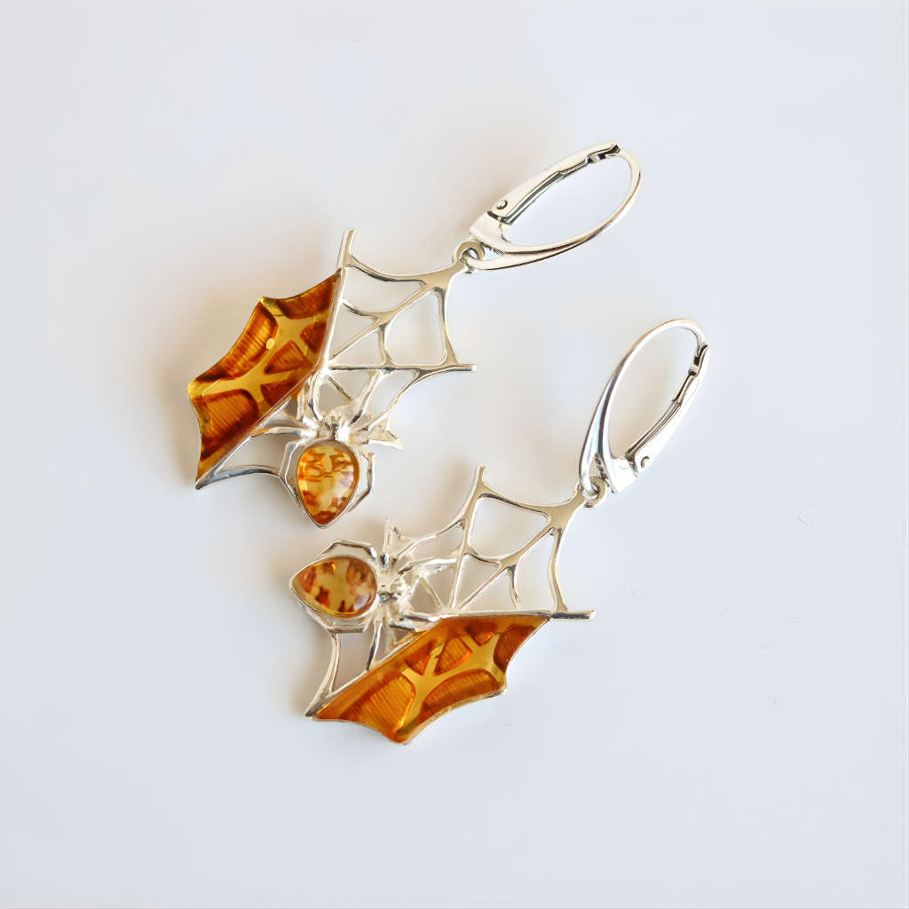 Spider web amber earrings with amber-colored stones on a light gray background