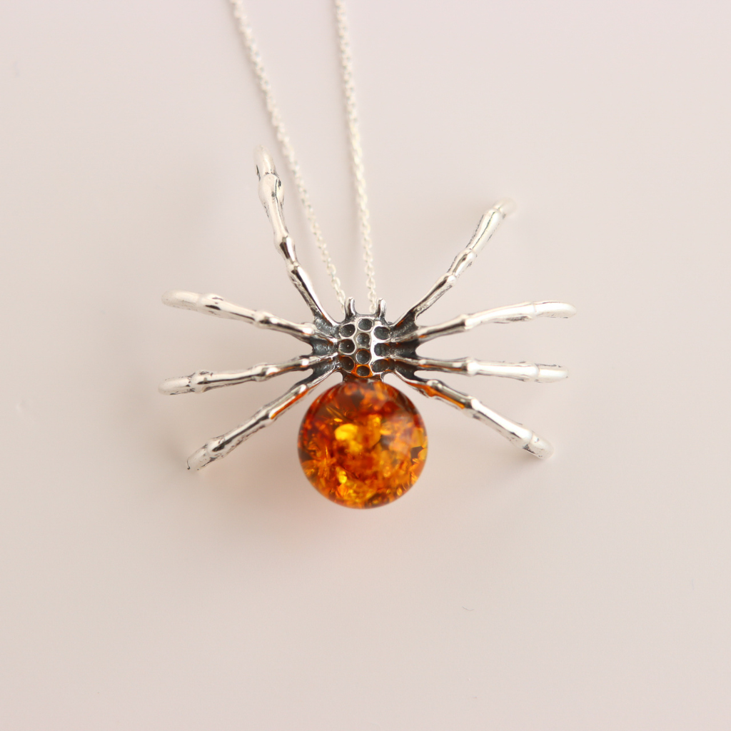amber necklace with Spider-shaped pendant. amber-colored sphere on a light background