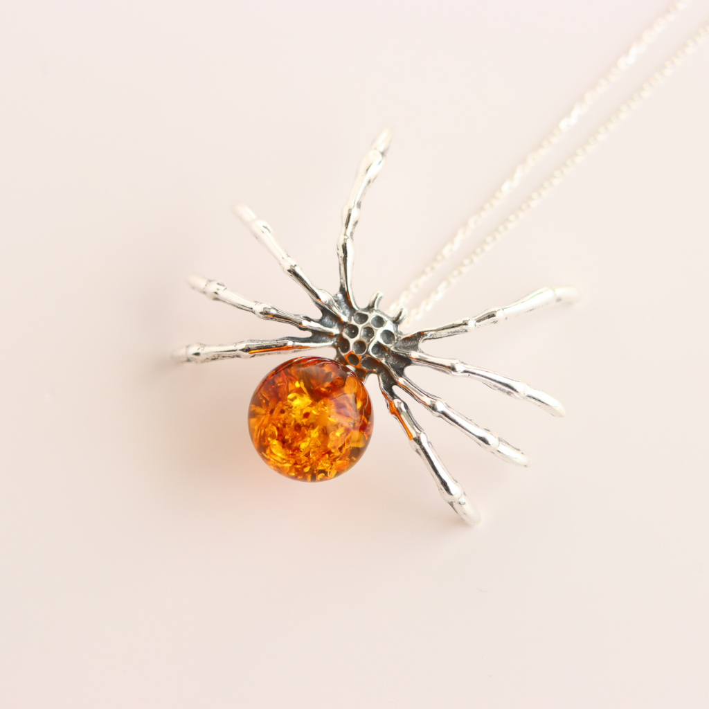 amber necklace with Silver spider-shaped pendant with a round amber stone on a light background
