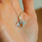 amber necklace with silver bat pendant  on a chain held in a hand.