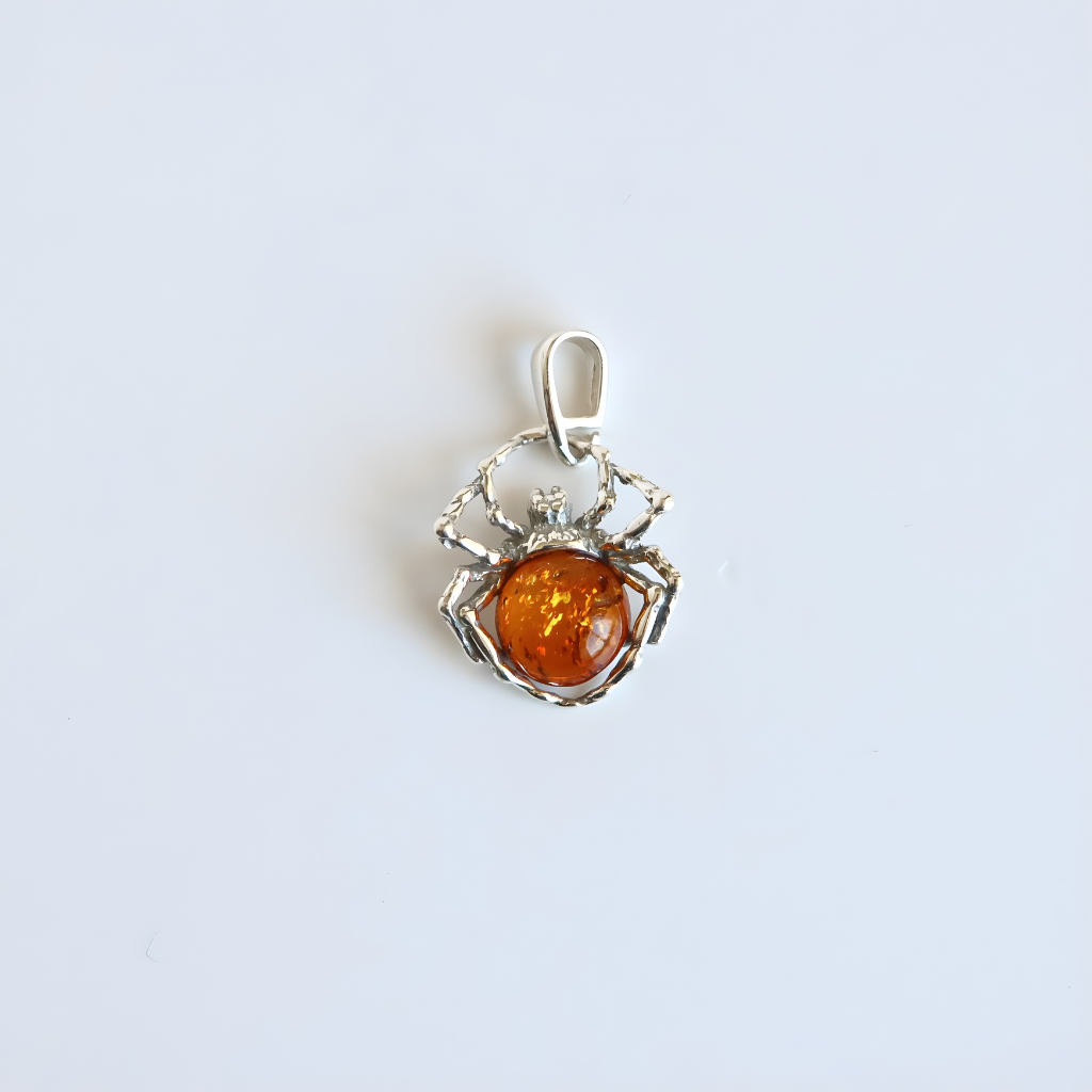 Silver amber spider pendant with a central amber stone on a light gray background