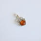 Silver amber spider pendant with a central amber stone on a light gray background