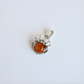 Silver amber spider pendant with a central amber stone on a light gray background