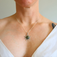 Person wearing a silver necklace with a amber sun pendant