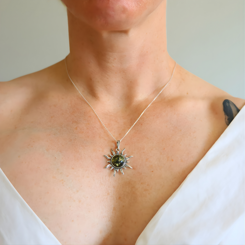 Person wearing a silver necklace with a amber sun pendant