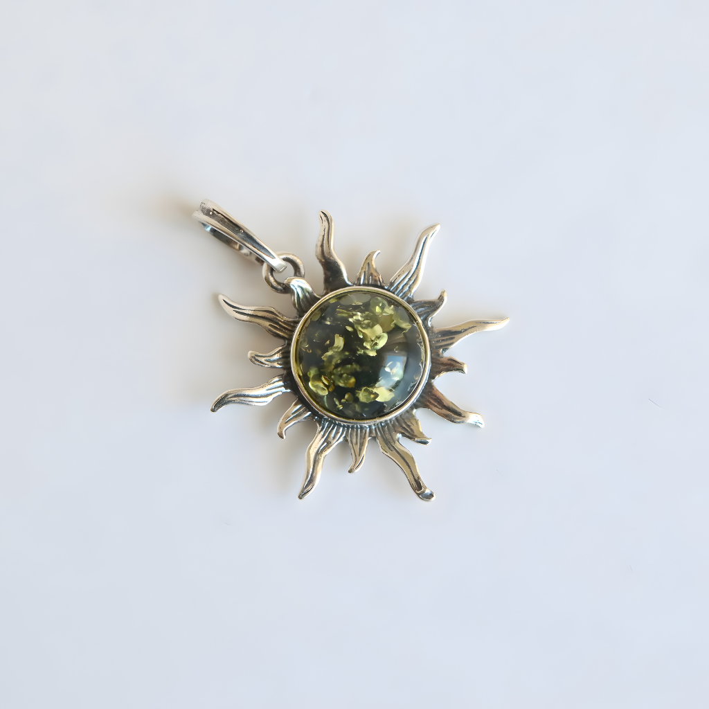 Silver amber sun pendant with a green gemstone on a white background