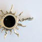 amber sun pendant with a black center on a light gray background