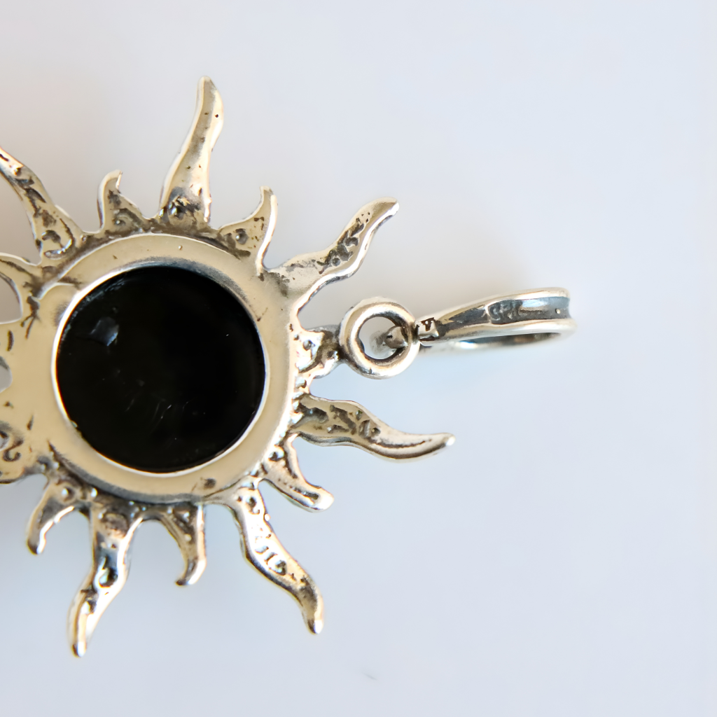 amber sun pendant with a black center on a light gray background