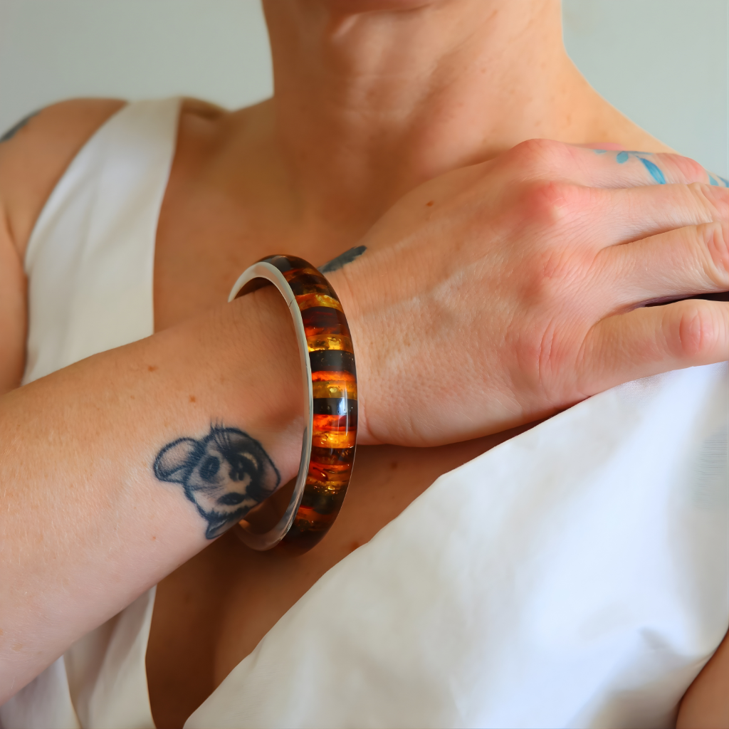 Person wearing a amber bangle bracelet on a white background