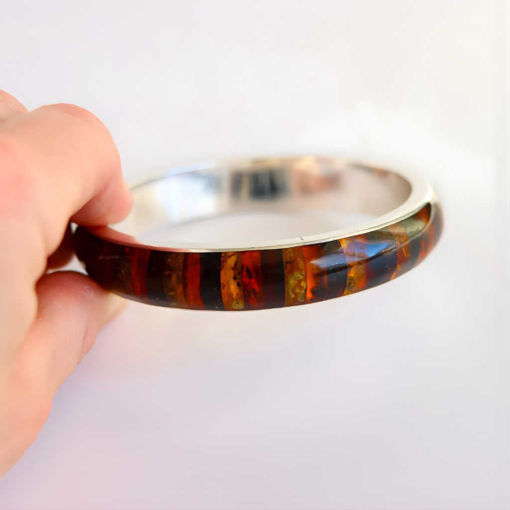 Hand holding a multicolored bangle bracelet against a light background