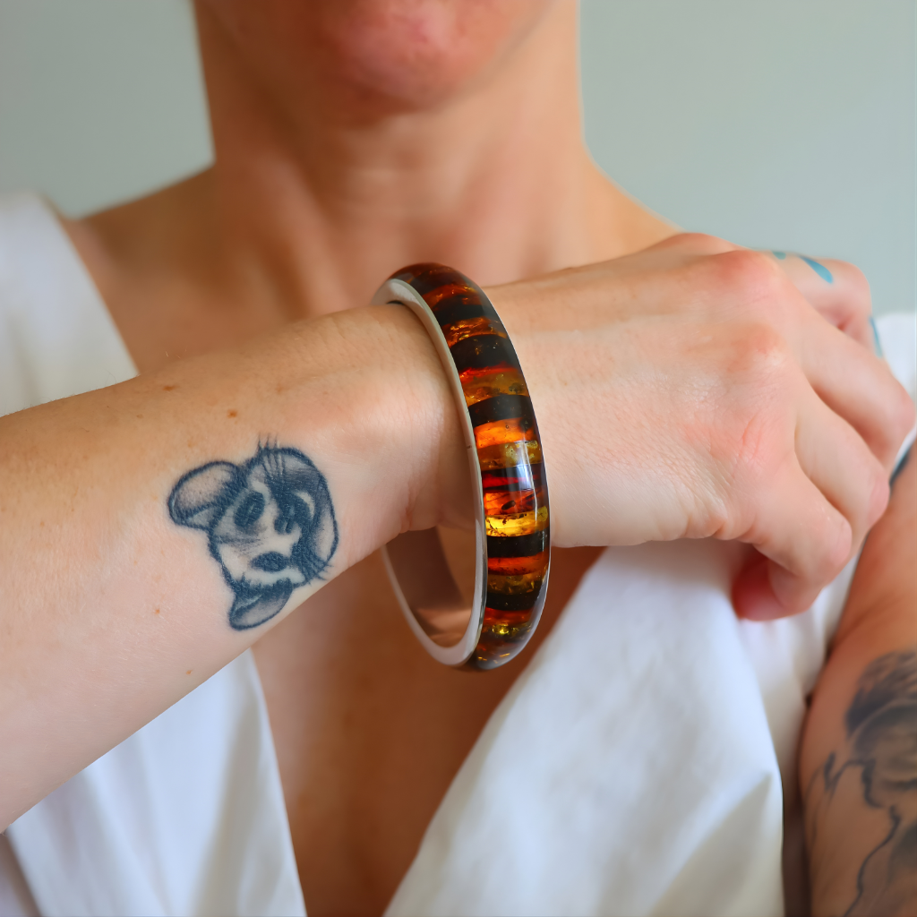 Person wearing a colorful amber bangle bracelet on a white background