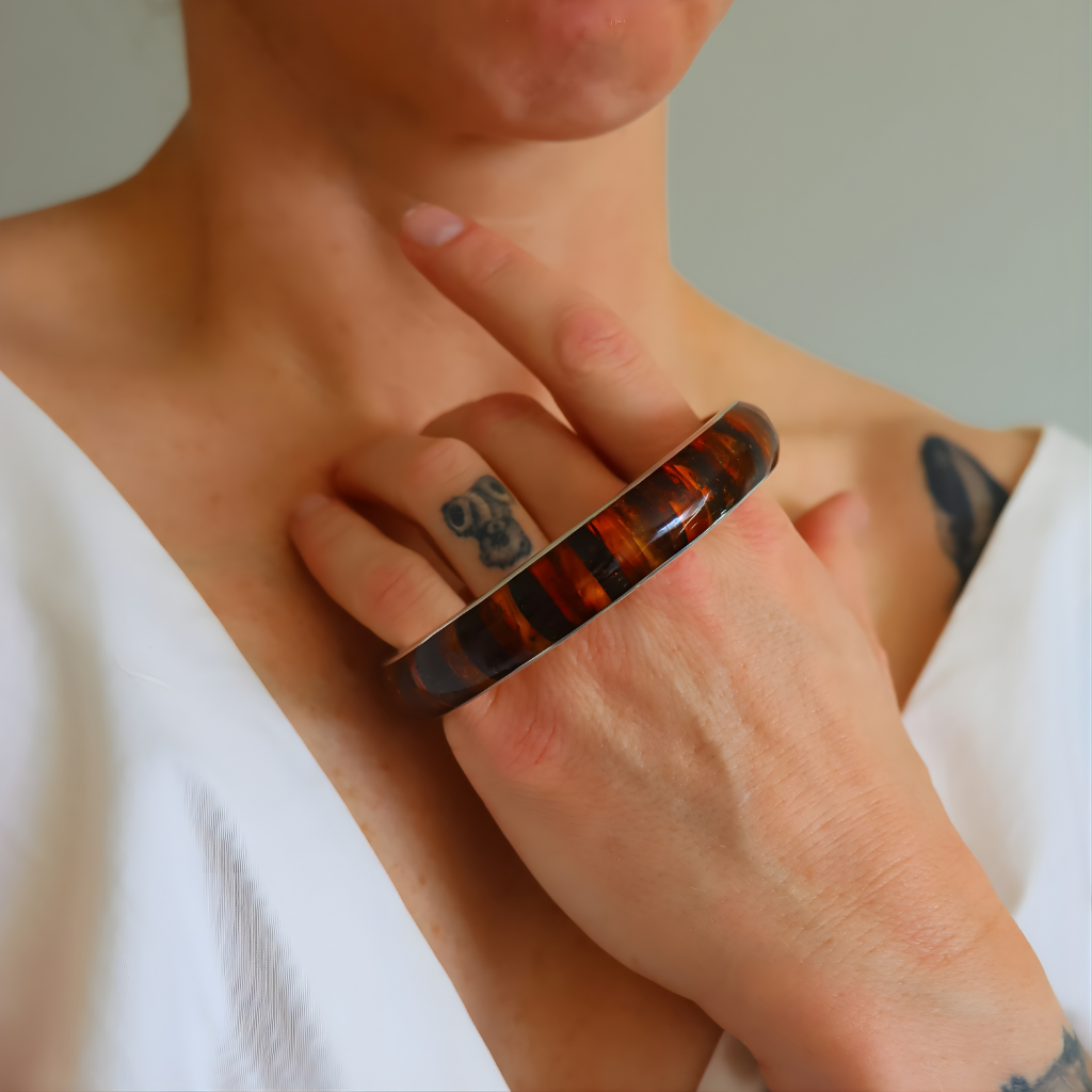 Person wearing a mosaic amber bangle bracelet featuring honey and and cognac colors.