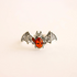 Bat ring with amber-colored gem on a beige background