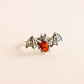 Silver bat ring with amber stone on a beige background