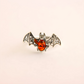 Bat ring jewelry with amber center on a beige background