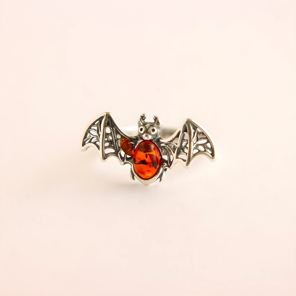 Bat ring jewelry with amber center on a beige background