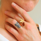 Close-up of a hand wearing gold butterfly ring with tattoos on the fingers.