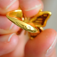 Gold butterfly ring held between fingers