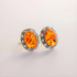 Pair of amber-stone clip on earrings with silver settings on a light gray background