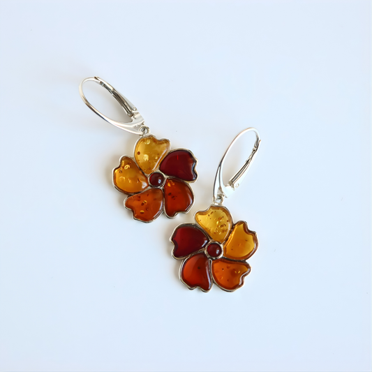 Flower-shaped amber earrings on a light blue background