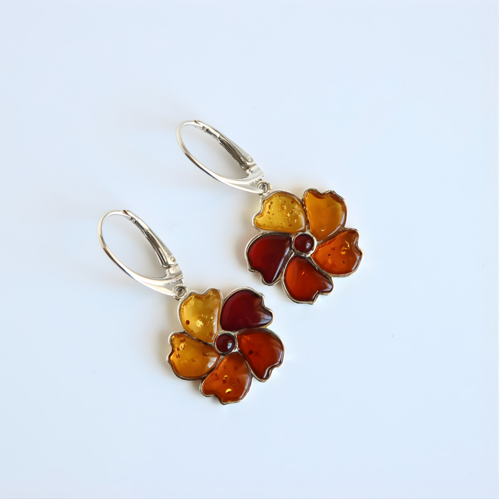 Pair of floral amber earrings with amber-colored flowers on a light blue background