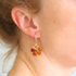Close-up of a person wearing colorful floral amber earrings.