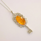 amber necklace with Silver key-shaped pendant with an amber stone on a light gray background