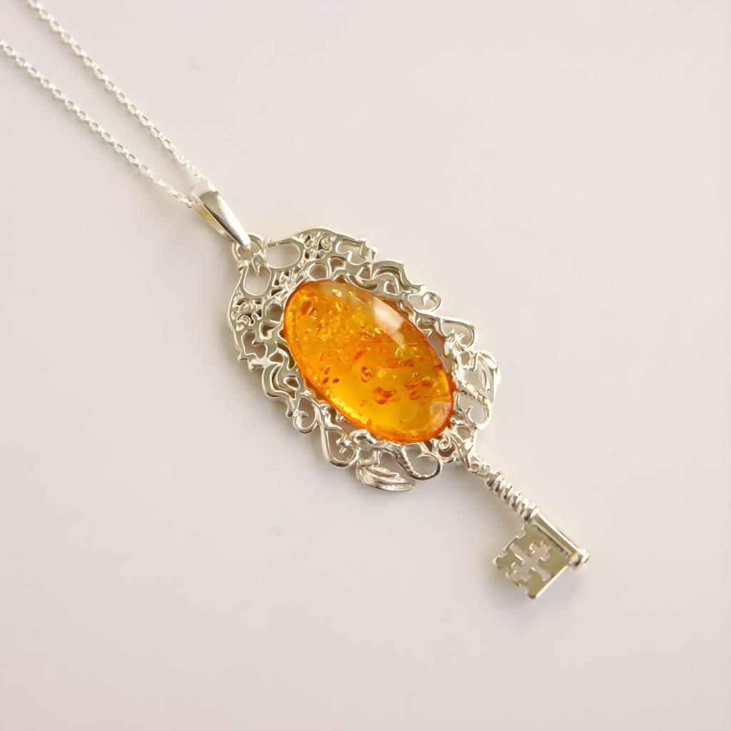amber necklace with Silver key-shaped pendant with an amber stone on a light gray background
