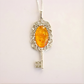 amber necklace with Silver key-shaped pendant with an amber-colored stone on a white background