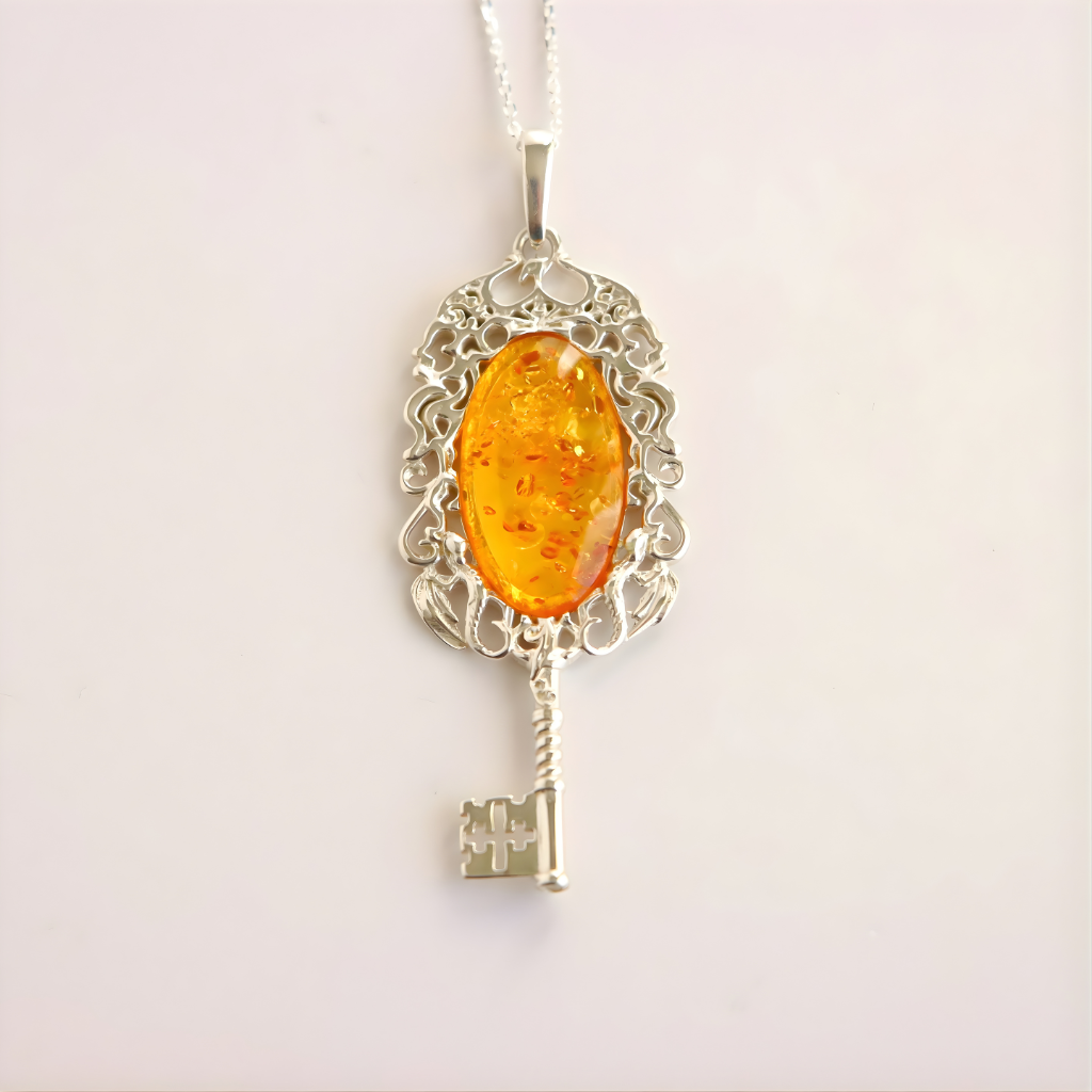 amber necklace with Silver key-shaped pendant with an amber-colored stone on a white background