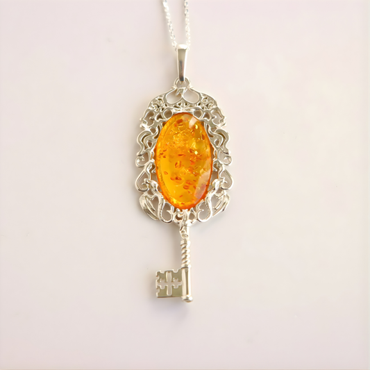 amber necklace with Silver key-shaped pendant with an amber-colored stone on a white background
