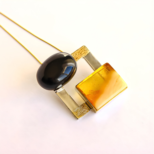 amber Necklace with black, blue, and gold pendant on a white background