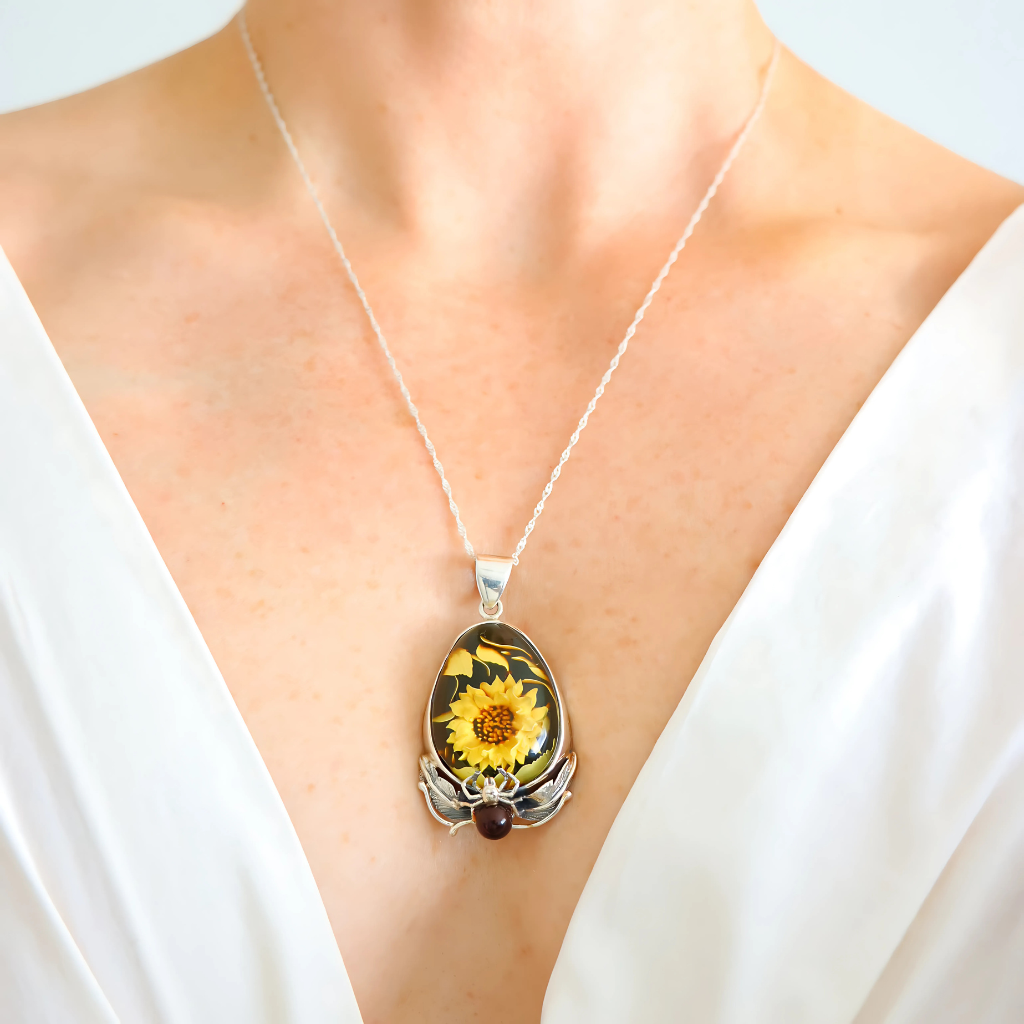 amber necklace with sunflower and spider on neutral background