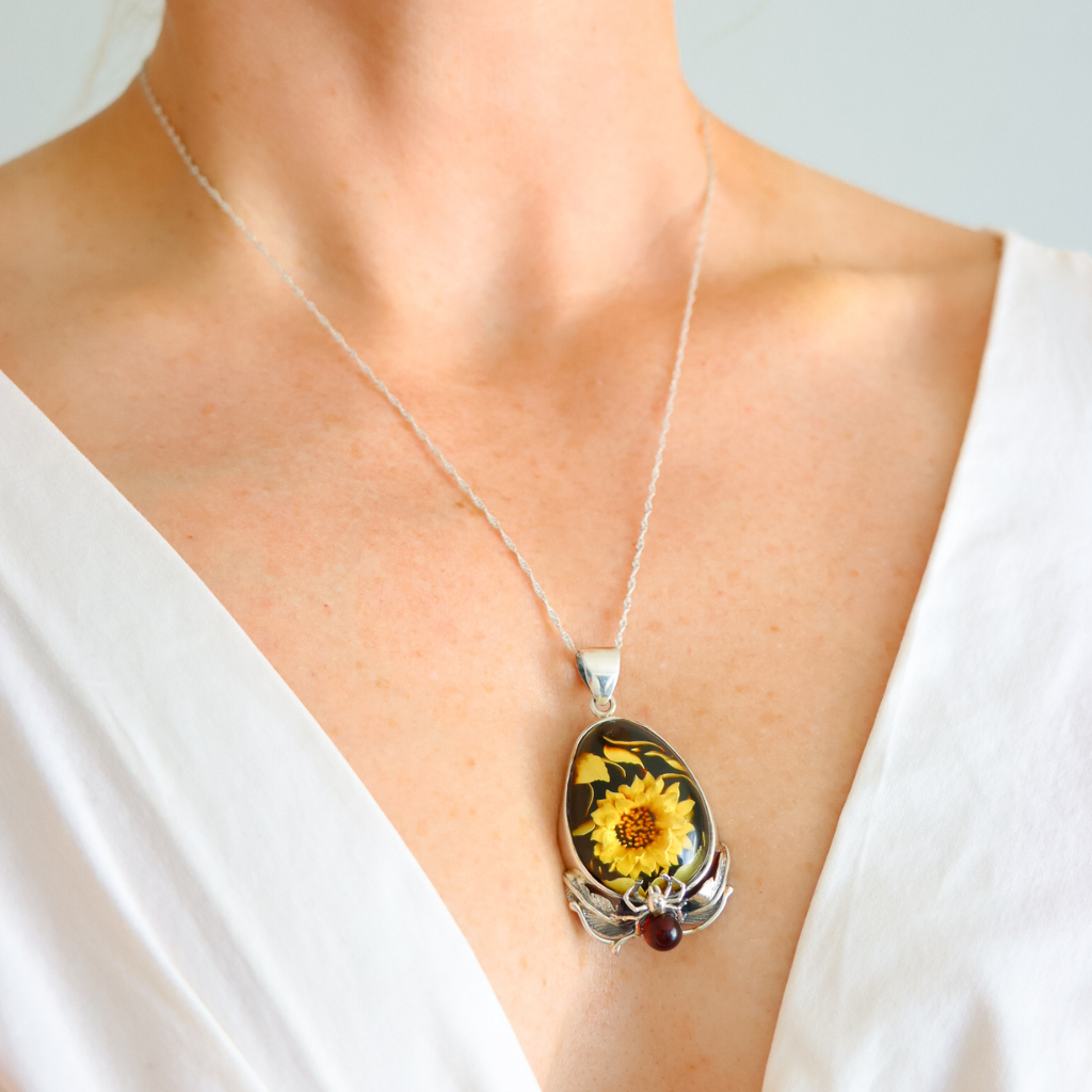 Amber Necklace with a sunflower pendant worn by a person in a white top