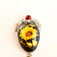 amber necklace with sunflower pendant and spider design on neutral background