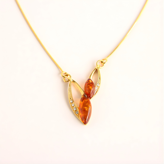 Gold amber necklace with a pendant featuring amber-colored stones on a white background